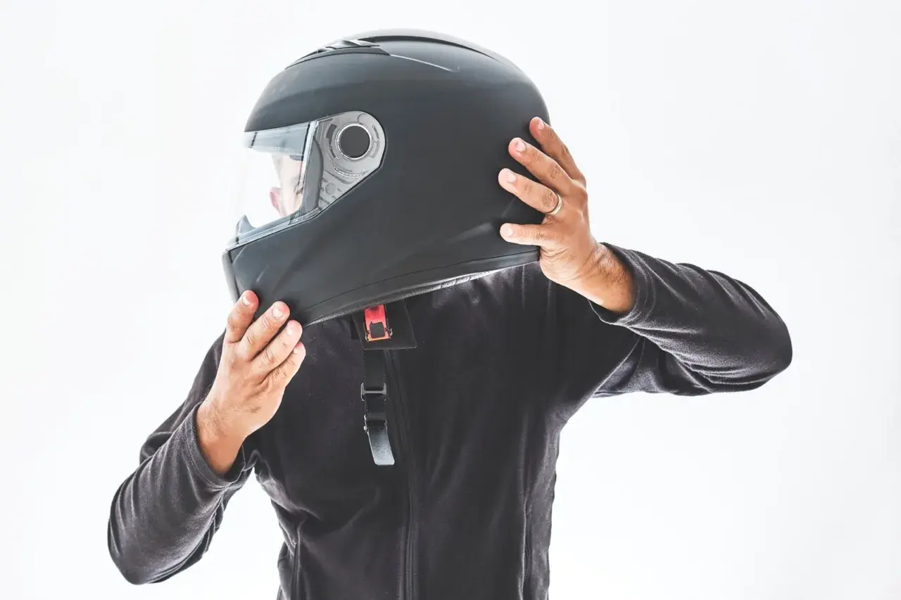 Persona indossa un casco nero, assicurandosi che sia ben saldo. È bene che il casco sia dotato di visiera per proteggere gli occhi.