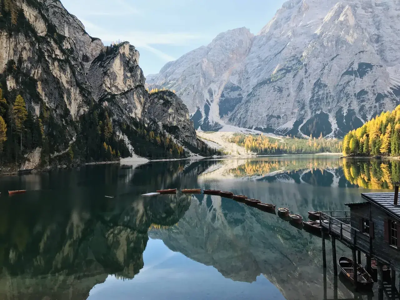 Un suggestivo itinerario al Lago di Braies e dintorni, con barche di legno ormeggiate e montagne maestose riflesse nell'acqua cristallina.