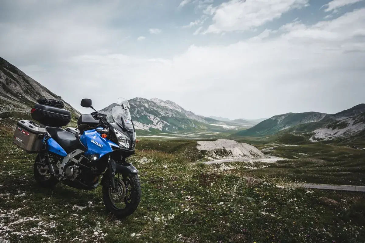 Moto blu pronta per esplorare il vasto campo imperatore, con montagne maestose sullo sfondo.