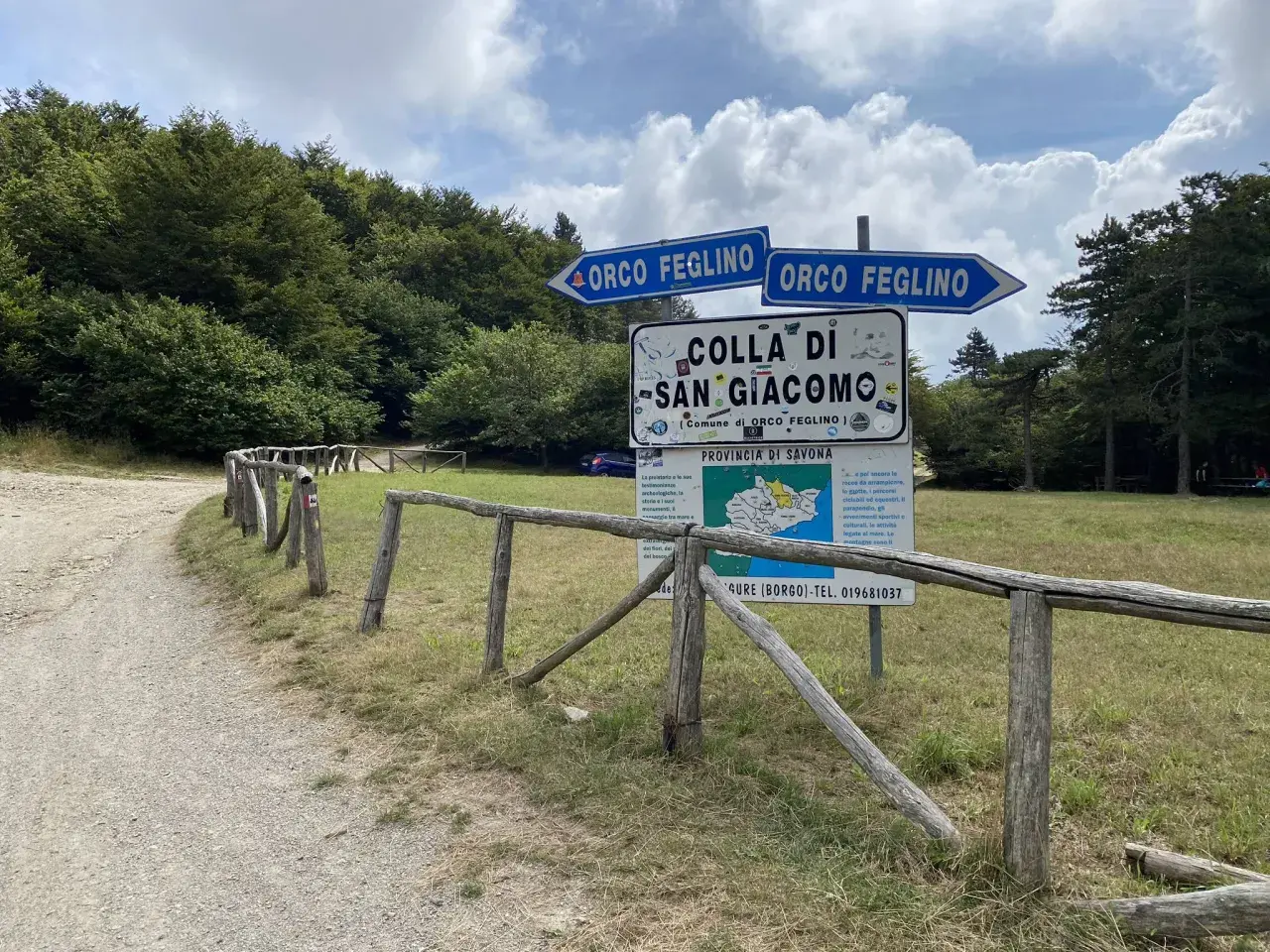 Segnaletica stradale indica la direzione per Orco Feglino e la Colla di San Giacomo, immersa nel verde di una foresta.