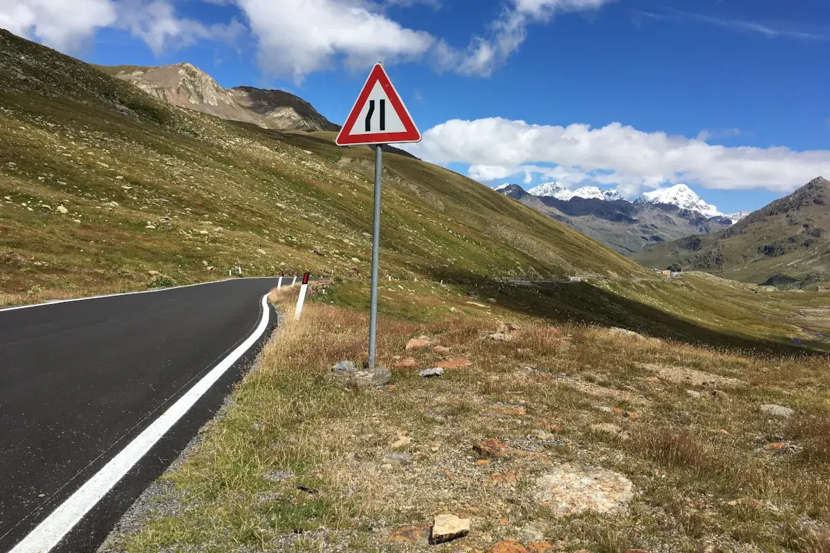 Strada di montagna con segnale di restringimento. Perfetto per sapere dove andare in moto, tra panorami mozzafiato e curve emozionanti.
