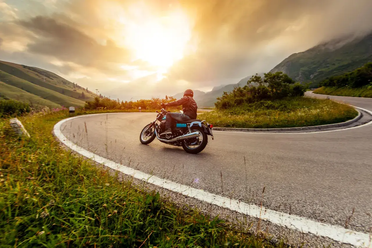 Motociclista percorre una strada tortuosa in Umbria, godendosi un'avventura di 3 giorni tra paesaggi mozzafiato al tramonto.