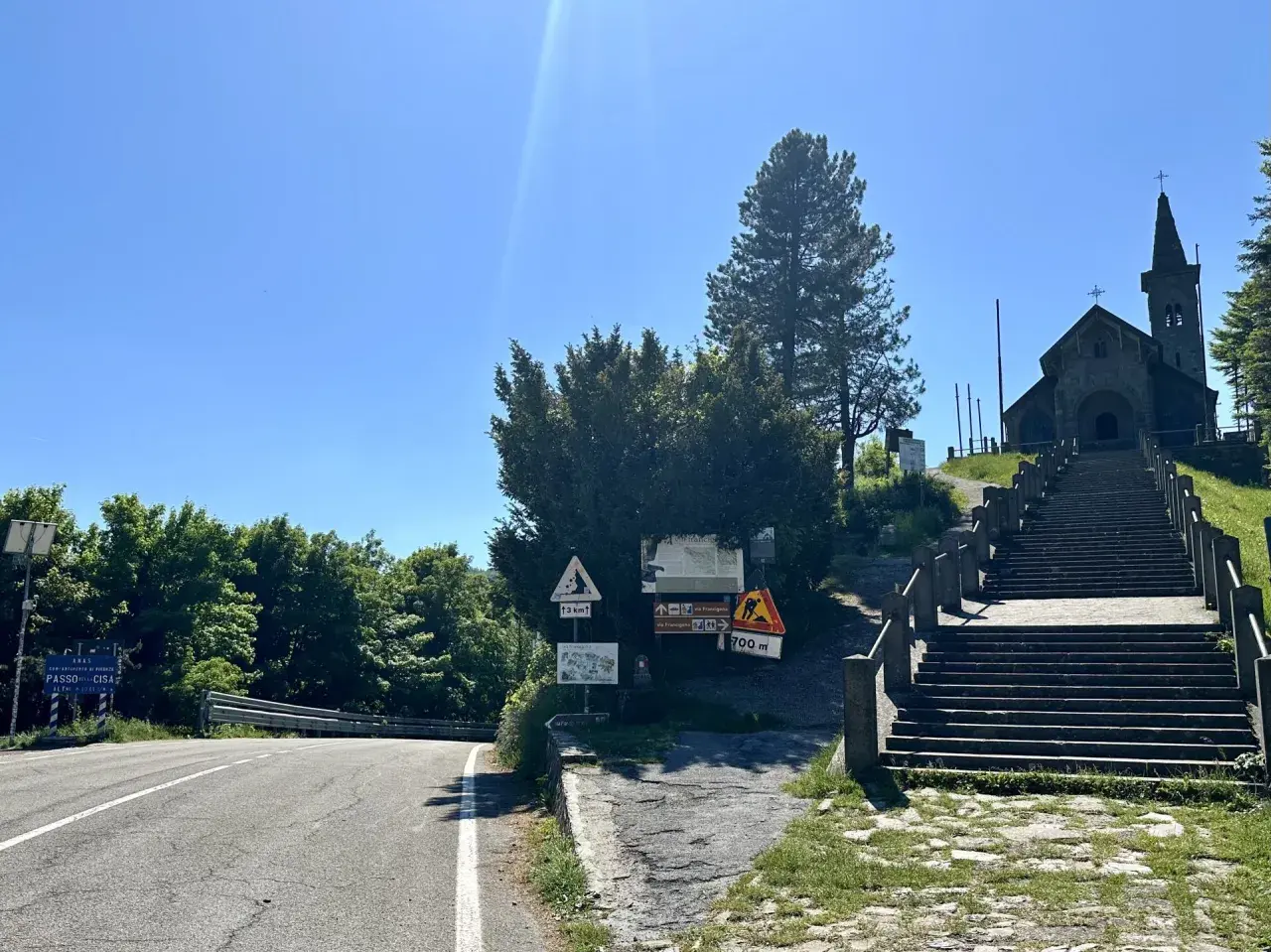 Strada e scalinata verso la chiesa in cima al passo della Cisa. Segnali indicano la via Francigena e la quota di 1041 metri.