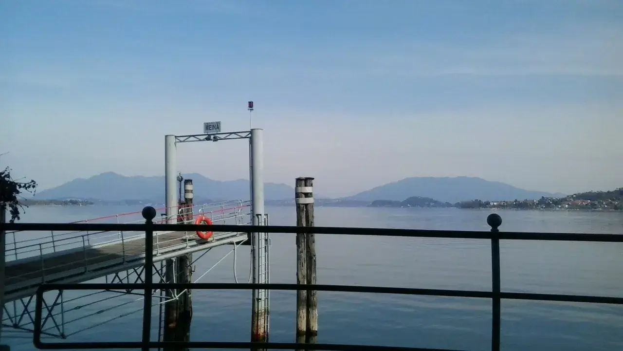 Molo di Meina, ideale per una pausa durante il giro del Lago Maggiore in moto. Montagne sullo sfondo.