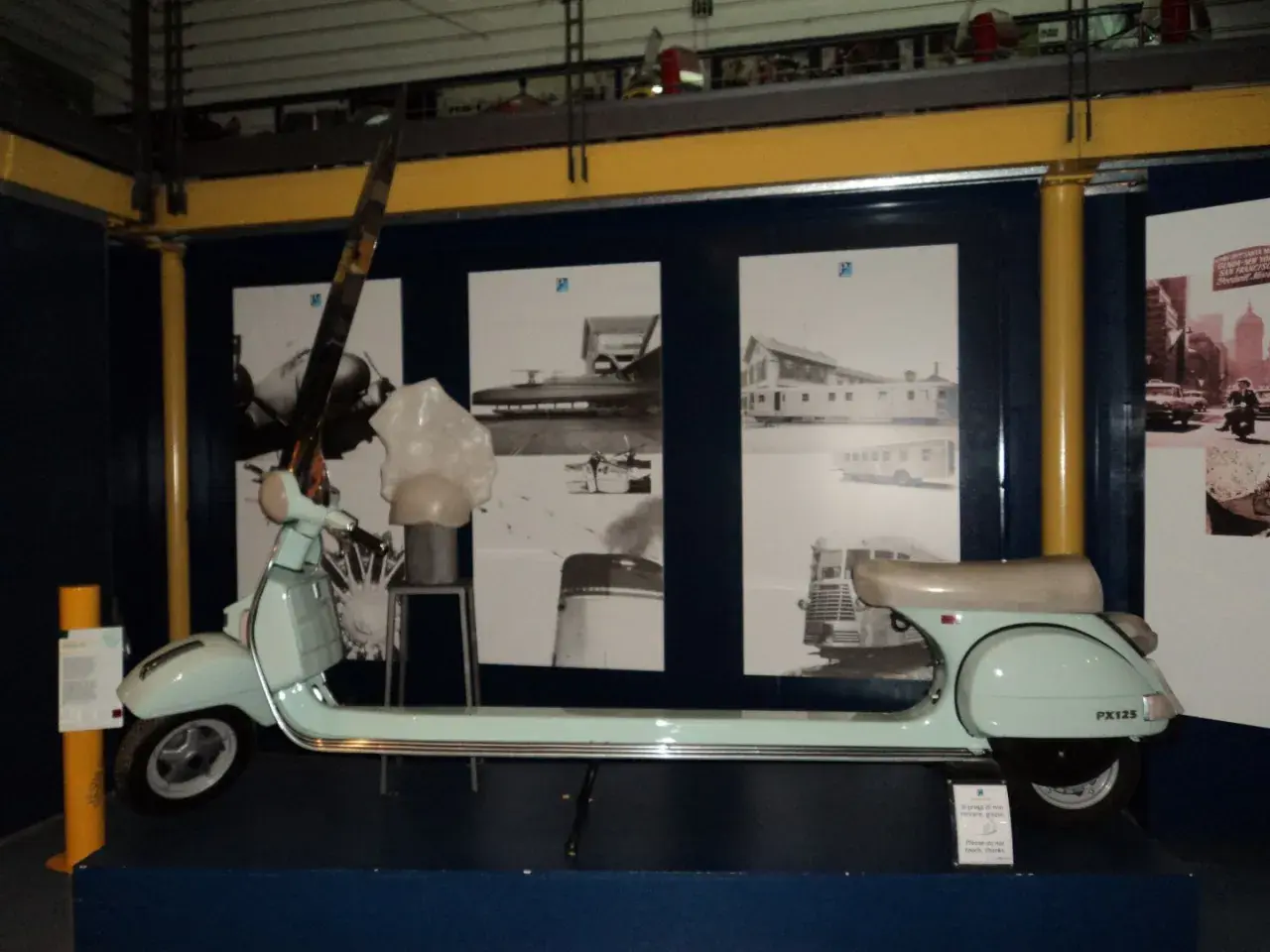 Vespa azzurra, simbolo dell'ingegno di Enrico Piaggio, esposta con foto storiche.