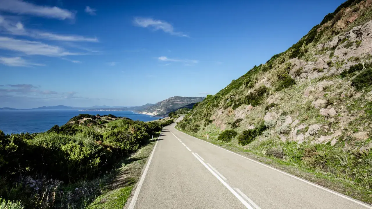 Strada panoramica lungo la costa sarda, un viaggio da Cagliari ad Alghero tra mare blu e macchia mediterranea.