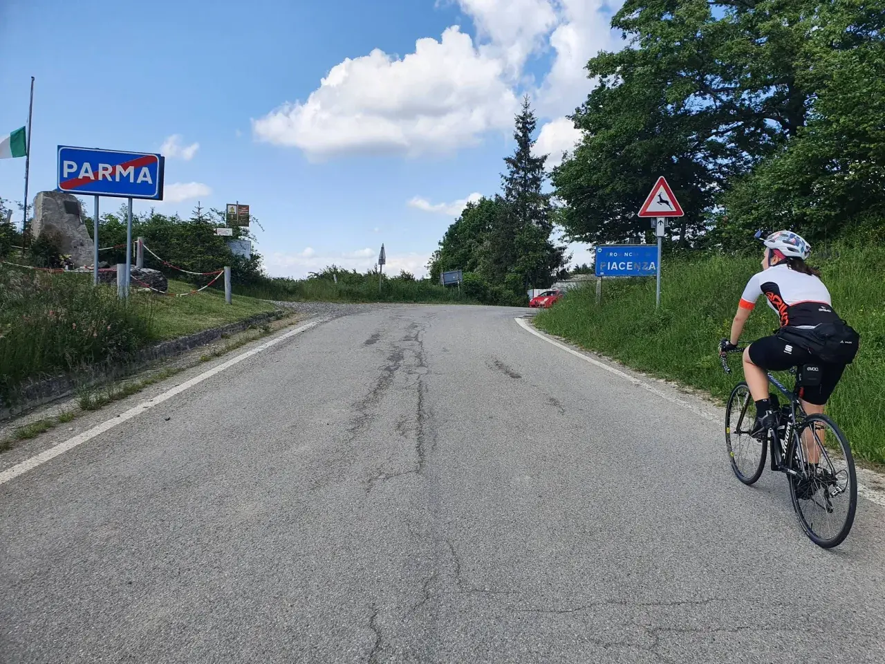 Ciclista in salita verso Piacenza, dopo aver superato il cartello di Parma. Il passo Pellizzone è un'ottima meta per gli amanti del ciclismo.