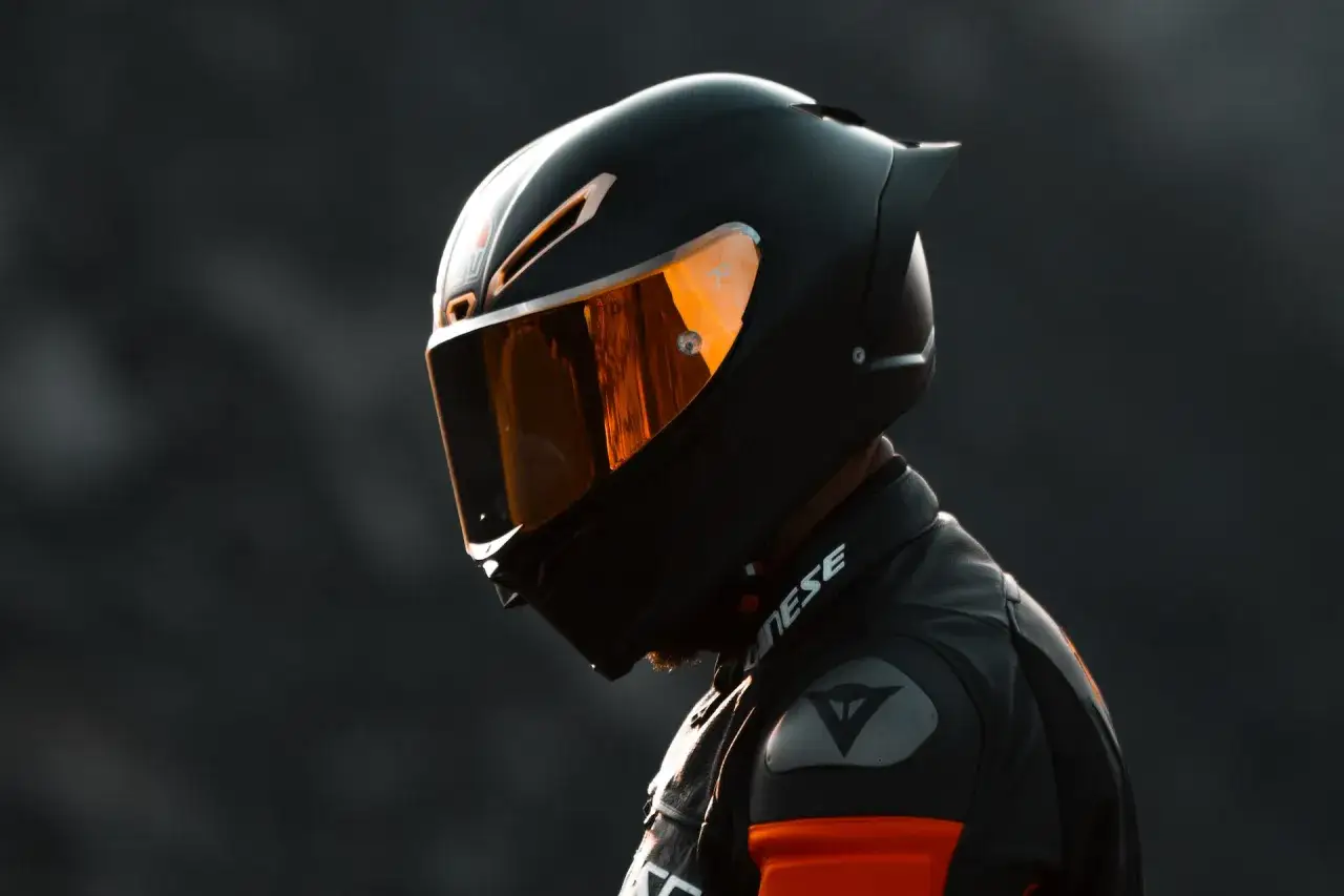 Casco da moto integrale nero con visiera arancione riflettente, pronto per la pista.