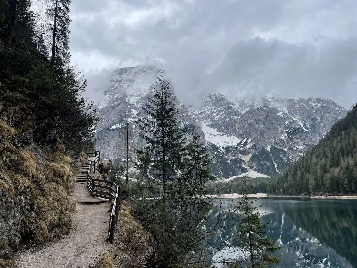 Sentiero da Brunico a Lago di Braies, con montagne innevate e un lago specchiato.