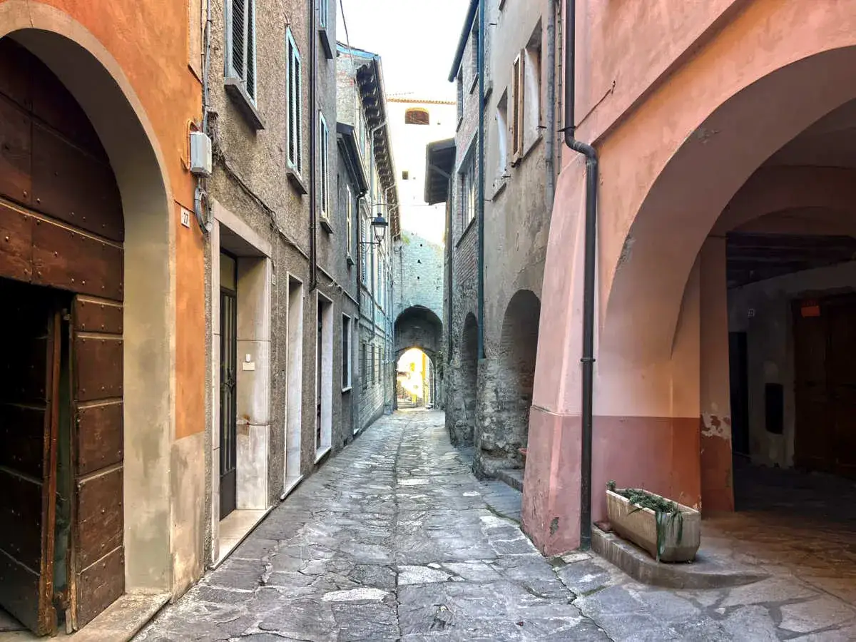 Un vicolo suggestivo a Varzi, con archi in pietra e facciate colorate. Un invito a scoprire cosa vedere in questo borgo medievale.
