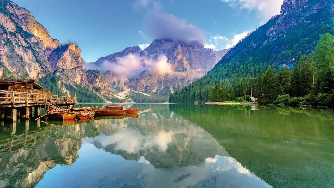 Un suggestivo itinerario al lago di Braies e dintorni: barche di legno ormeggiate, rifessi montani sull'acqua cristallina e un rifugio alpino.
