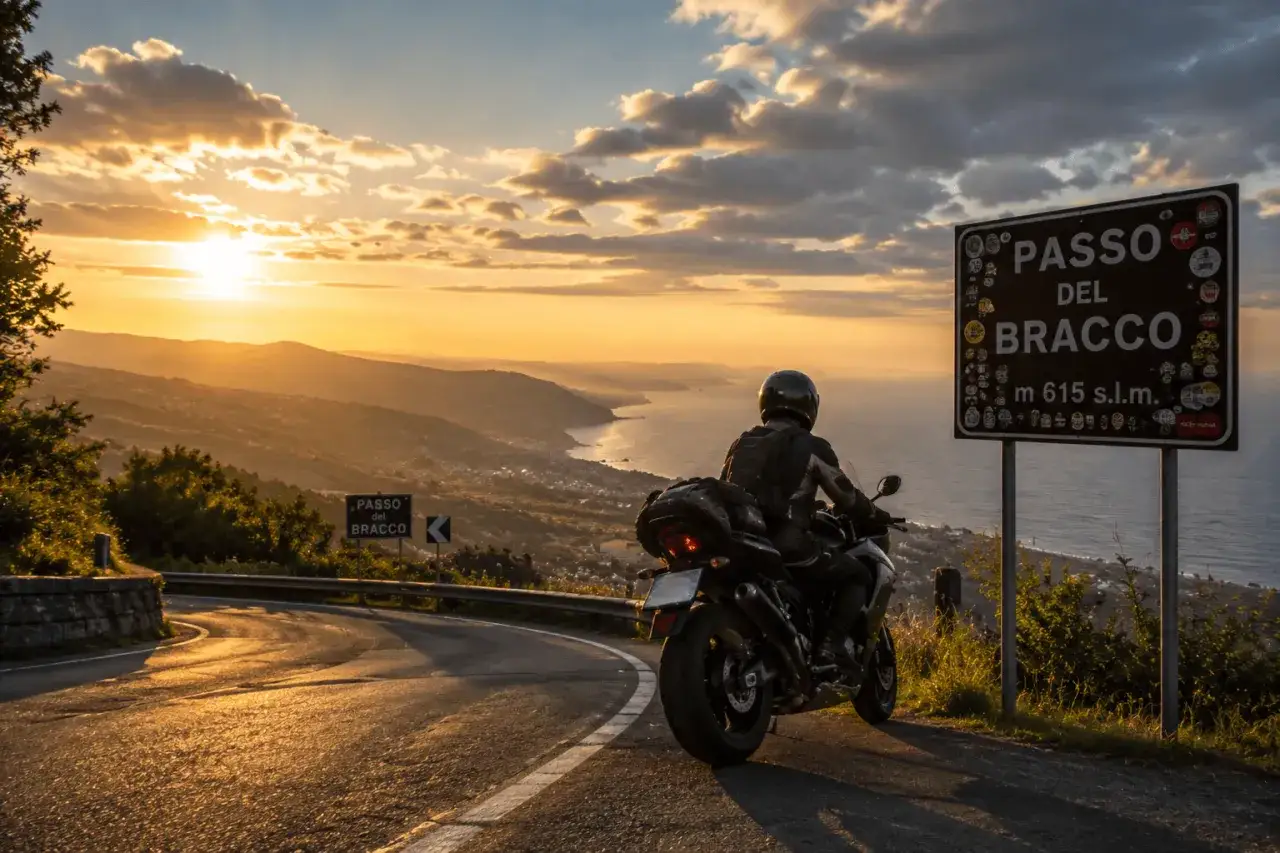 Motociclista al tramonto sul Passo del Bracco, con vista panoramica sulla costa e sul mare.