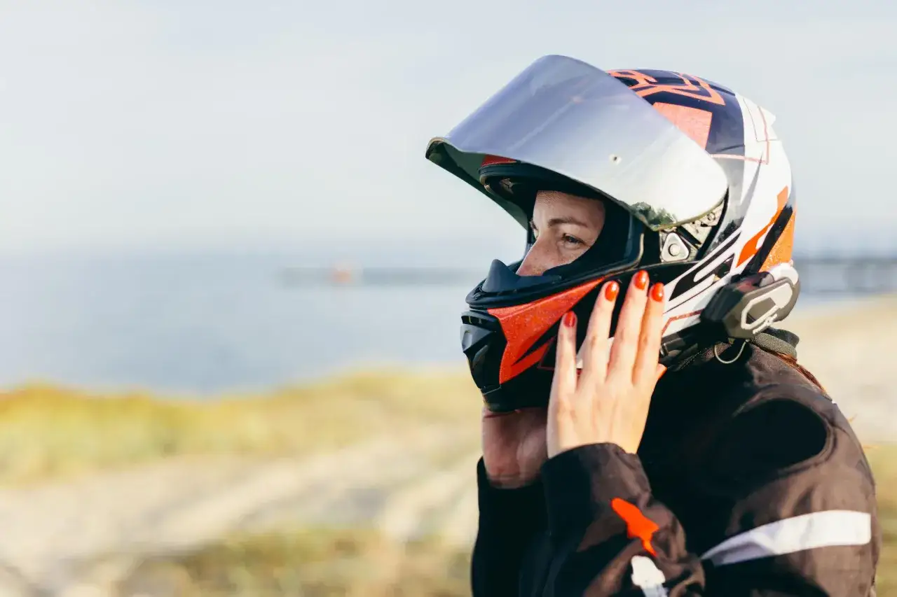 Donna con casco da moto colorato, con visiera riflettente. Un gesto per capire come non far appannare la visiera del casco.