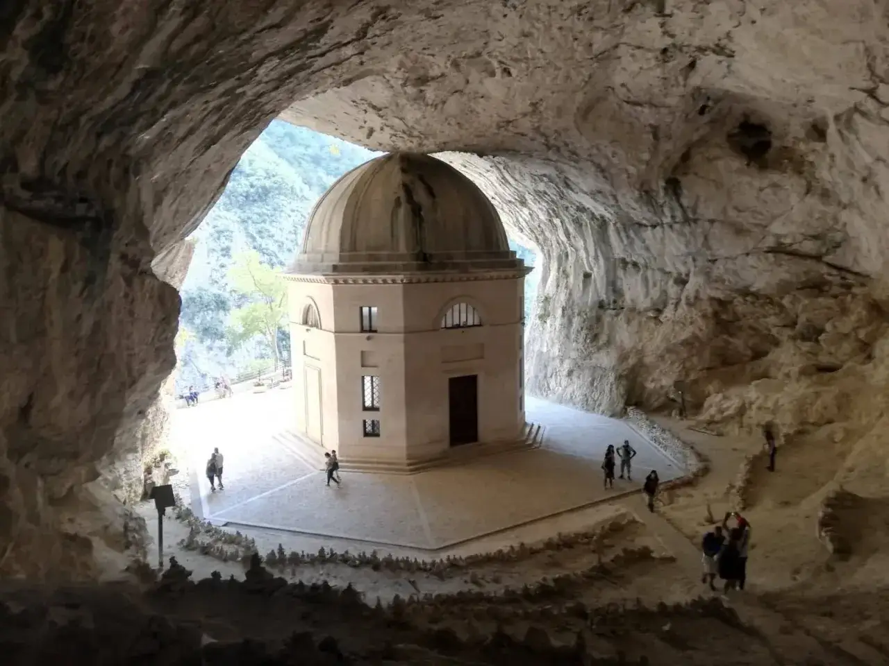Il tempio del Valadier, un'architettura ottagonale con cupola, incastonato in una grotta naturale. Turisti ammirano la struttura e il paesaggio circostante.