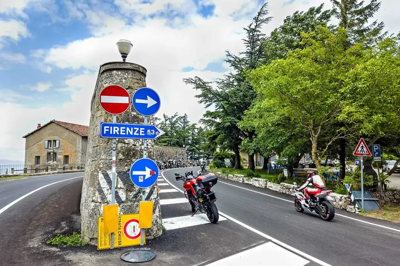 Segnaletica per Firenze sulla strada statale 67 tosco romagnola, con moto parcheggiate e una in transito.