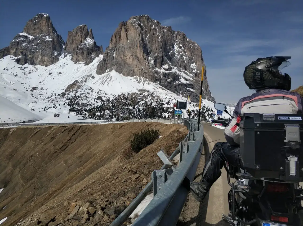 Motociclista ammira maestose vette innevate, godendosi i passi bergamaschi in moto.