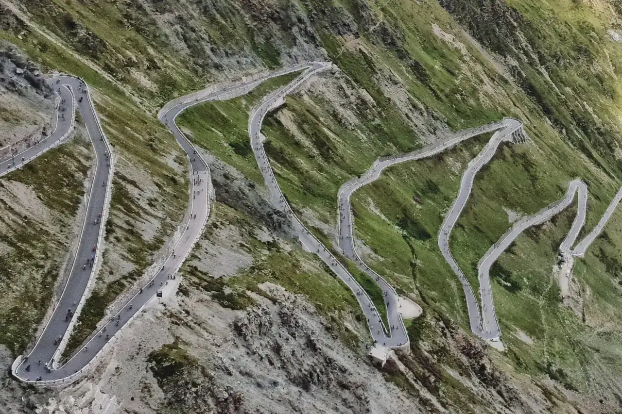 Ciclisti affrontano le curve a tornante del giogo di Santa Maria, una strada alpina mozzafiato.