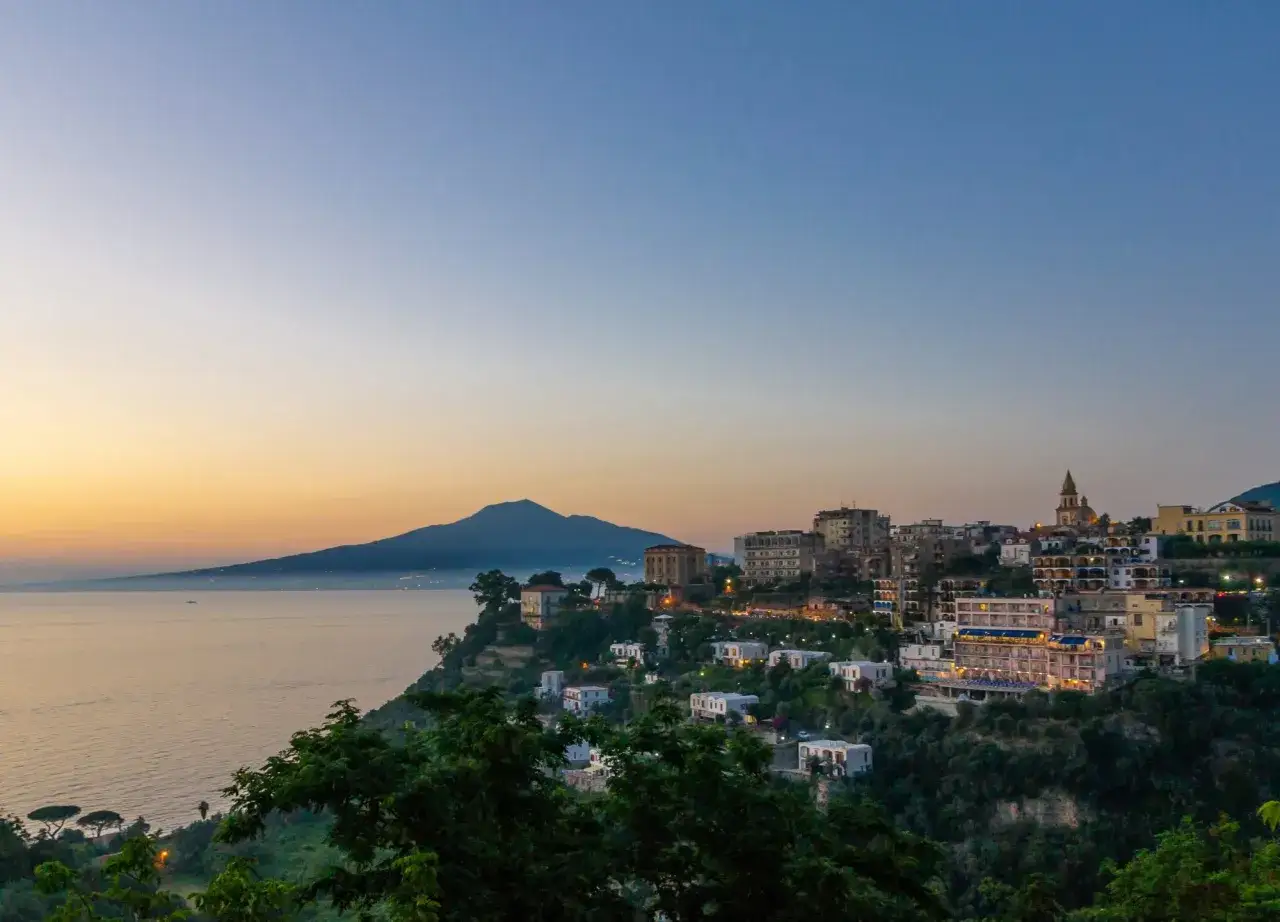 Vico Equense cosa vedere: un panorama mozzafiato al tramonto con il Vesuvio sullo sfondo e il mare che abbraccia la costa.