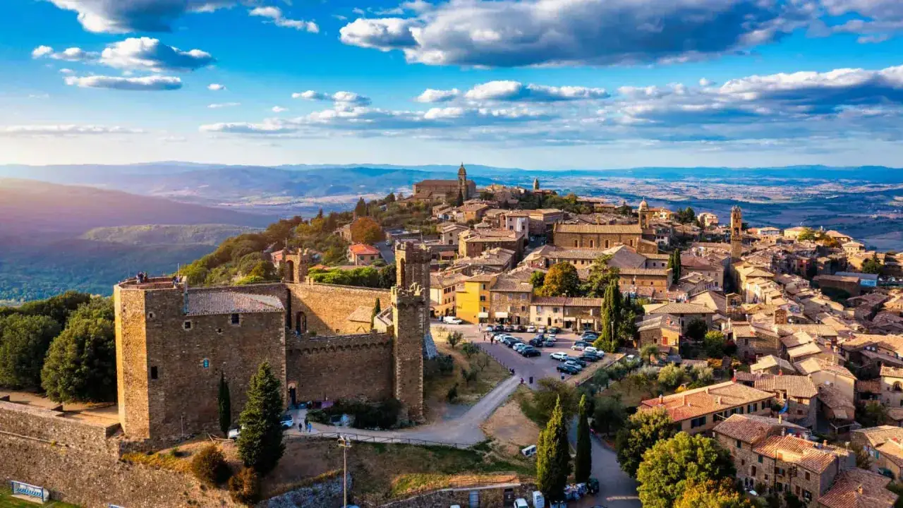 Borghi da visitare in 2 giorni: un castello medievale domina un paese collinare toscano, con tetti in terracotta e un panorama mozzafiato.