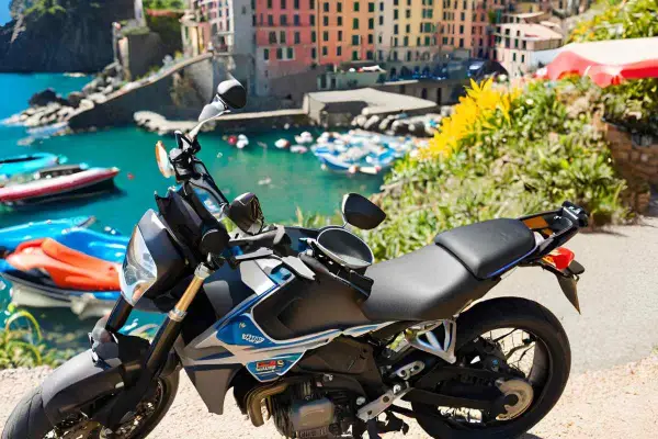 Moto parcheggiata con vista sul mare e case colorate della Liguria. Un'avventura su due ruote tra i passi liguri.